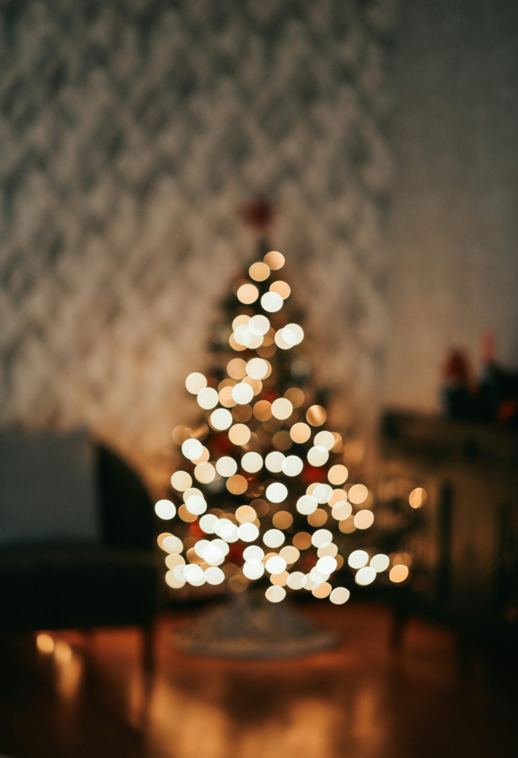 A softly blurred Christmas tree glowing with warm lights, creating a cozy holiday atmosphere that reflects the inviting feel of a well-staged home.