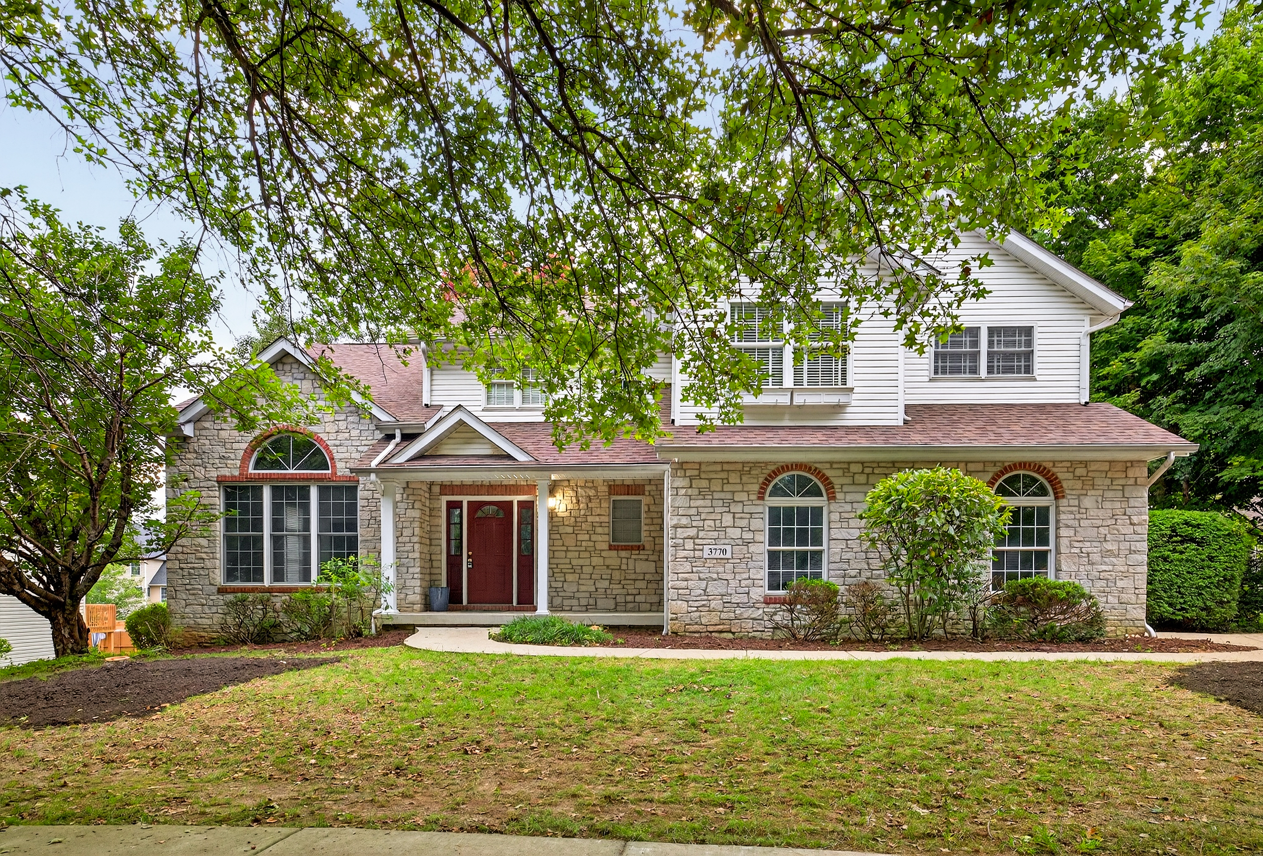 Photo of the front of the home that was just sold. It is a well-kept two story home with trees and a front lawn.